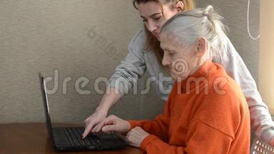 女孙女教她年迈的祖母使用笔记本电脑